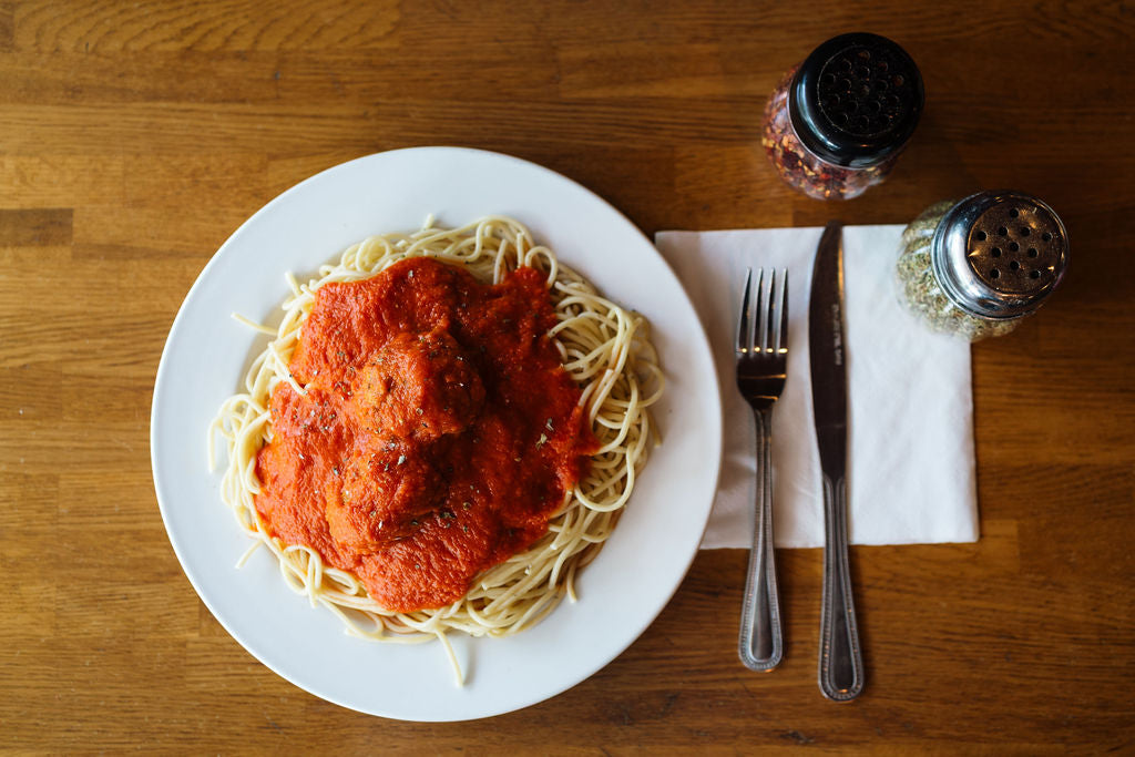 fresh spaghetti and meatballs with silverware and toppings at Joe's Pizza and Restaurant